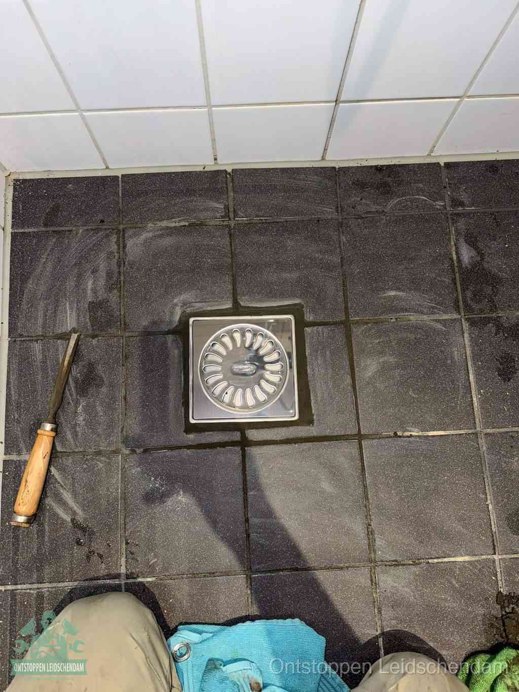 Een RVS doucheputje in een betegelde badkamervloer, zelf je badkamer ontstoppen in Leidschendam