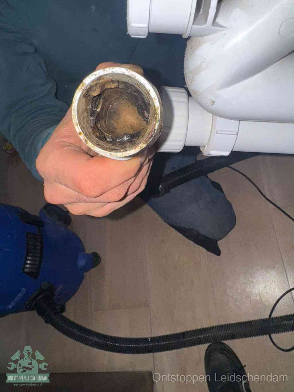 Een losgekoppeld PVC-afvoerbuisstuk dat van binnen volledig is dichtgeslibd met vet en vuil, de meest voorkomende oorzaak van verstoppingen in Leidschendam