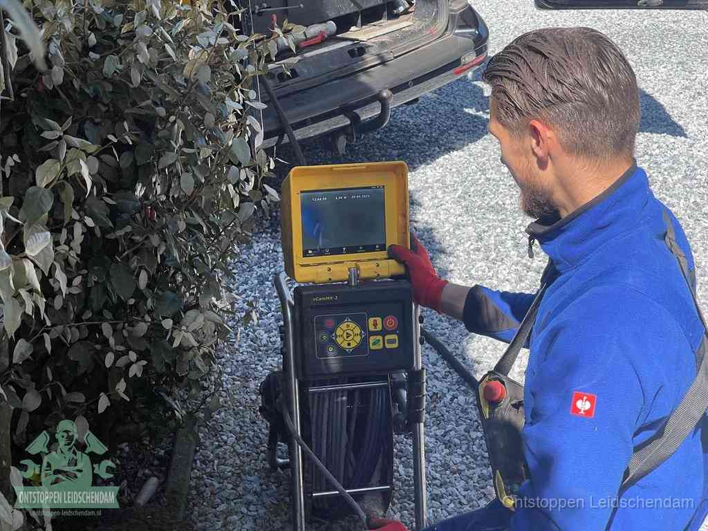 Een monteur bedient een rioolinspectiecamera met monitor en haspel om de verstopping in beeld te brengen in Leidschendam
