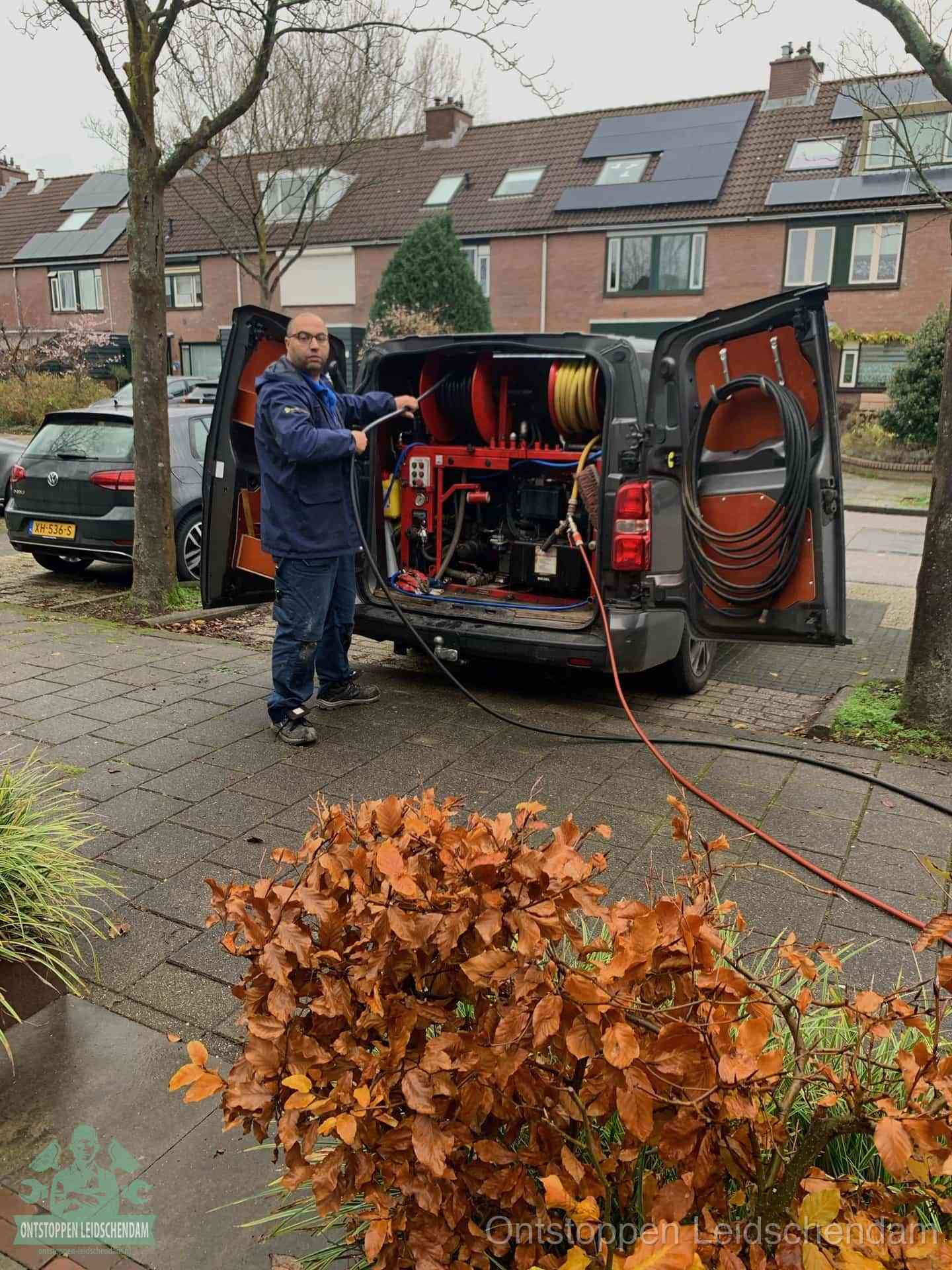 Een monteur staat bij zijn open bestelbus met hogedruk-rioolreinigingsapparatuur, klaar om binnen 30 minuten uit te rukken voor een spoedverstopping in Leidschendam