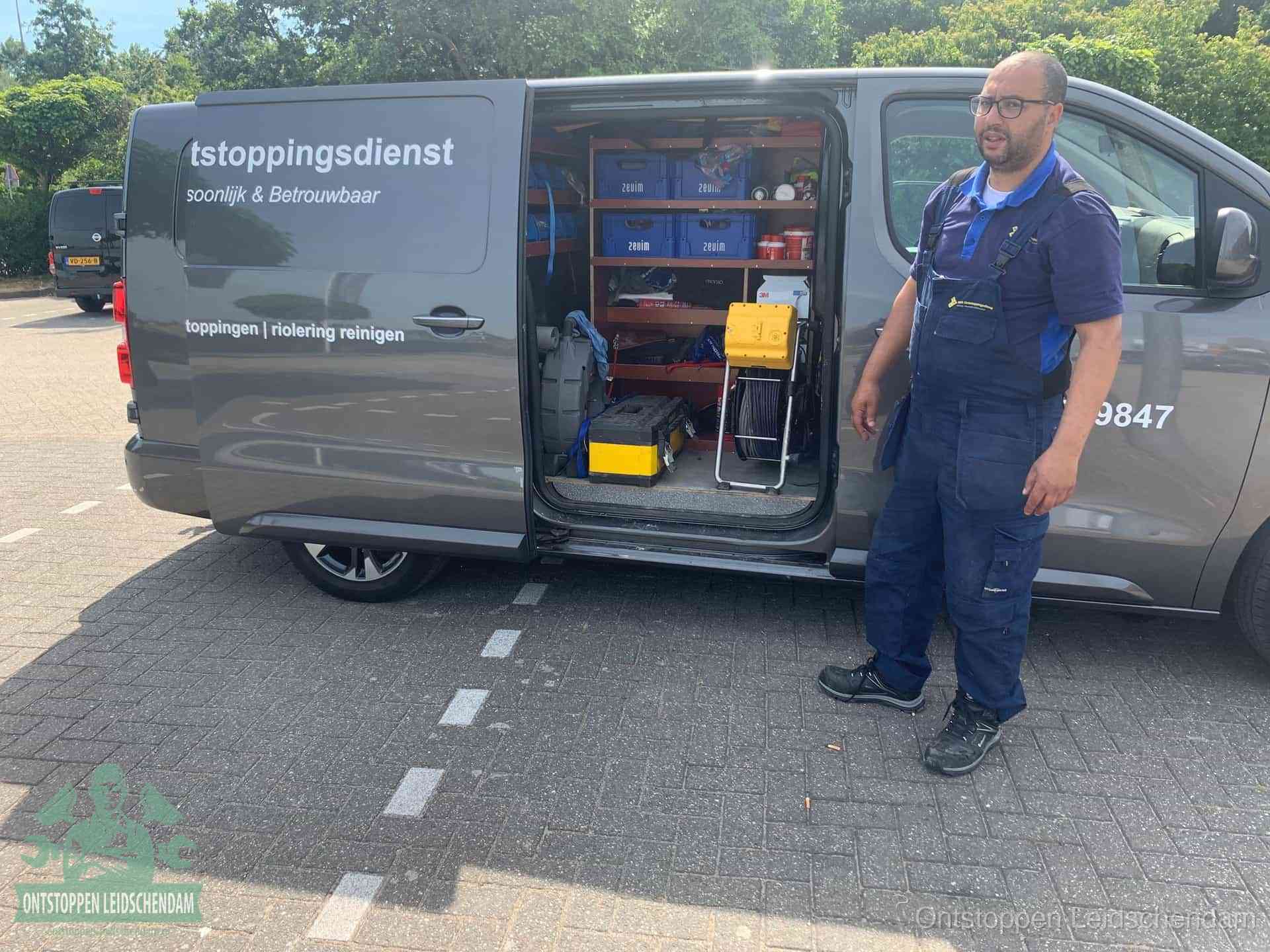 Een monteur staat klaar bij zijn bedrijfsbus met gereedschap, de vaste werkwijze van de ontstoppingsdienst in Leidschendam